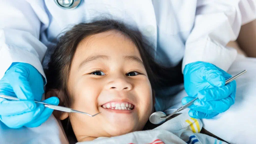 paediatric dentist carrying out an Oral Health Examination on a young asian girl