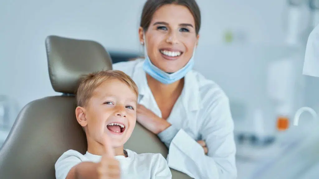 friendly woman dentist with a young boy smiling after dental emergency